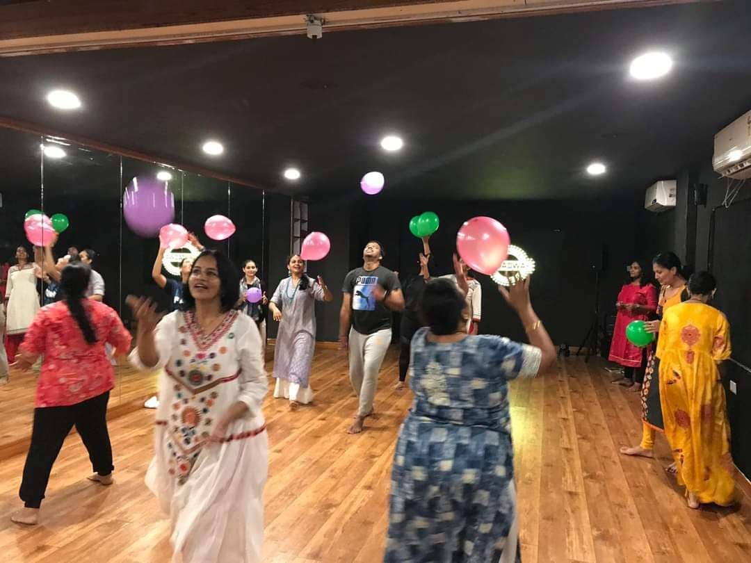 Participants tossing coloured balloons together in a dance studio
