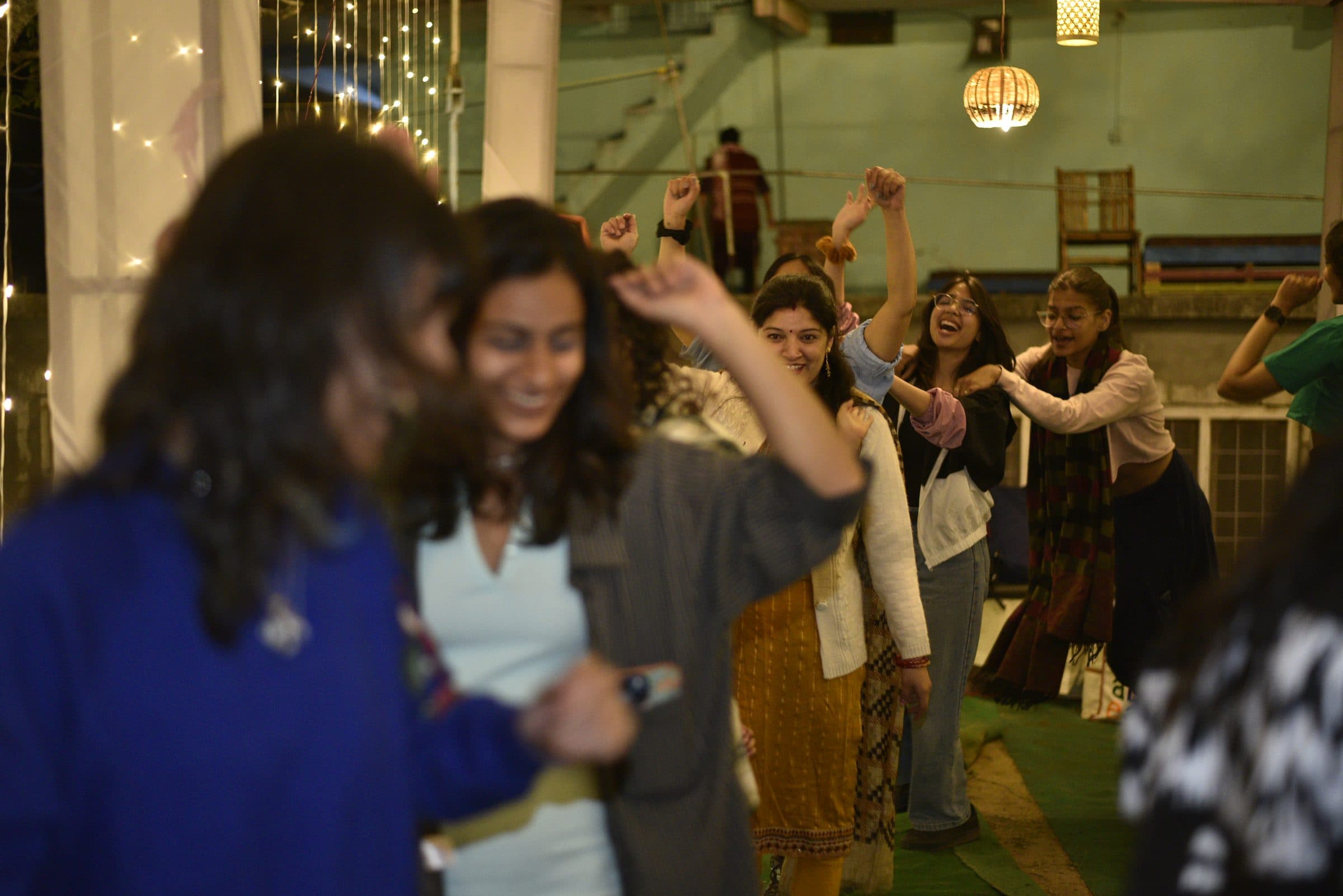 Participants in a row at an evening workshop, laughing and dancing with their arms raised